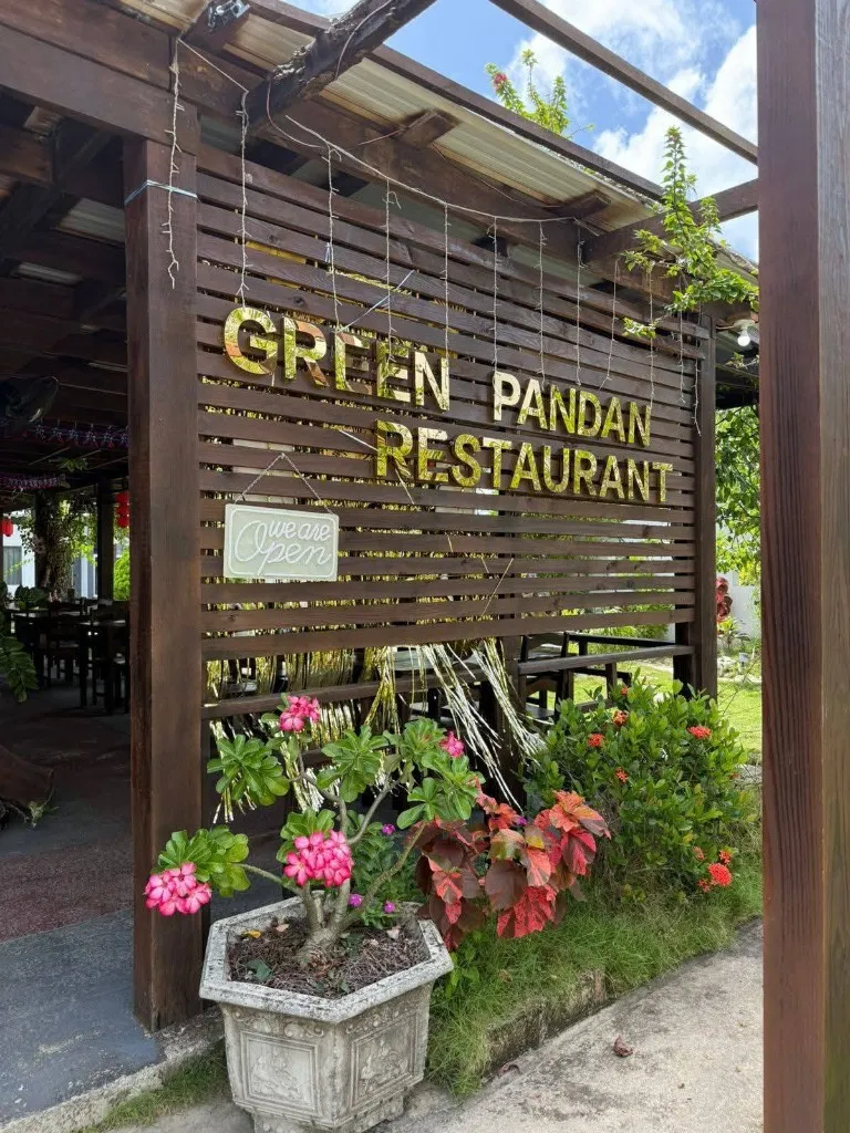The Green Pandan Restaurant sign on wooden slats, with flowers in front